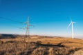 Windmill and electricity pylon on blue sunset sky