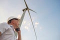 Windmill engineer talking on the phone on windmill and sky background. A man in a helmet supervises the operation of the electric