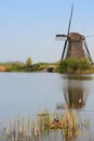 A windmill facing a house with a bird nest on the foreground bottom right corner in vertical view