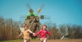 Windmill farm landscape. Netherlands village. Old wooden wind mills. Boy and girl playing and runing on green field Royalty Free Stock Photo