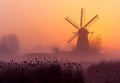 Windmill in foggy spring sunrise. Colorful landscape with old windmill in polder landscape Royalty Free Stock Photo