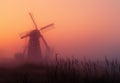 Windmill in foggy springtime morning. A yellow windmill rises from a misty field Royalty Free Stock Photo