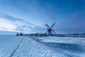 Windmill by frozen river in winter