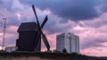 Windmill and high-rise building at the stormy evening and purple sunset