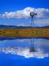 Windmill on Hillside in Countryside Rural America with Sky and Clouds Reflection in Water Pond Lake Reflect