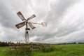 Windmill in the middle of the field under the gloomy sky in Holland Royalty Free Stock Photo