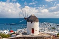 Windmill on mountain by sea in Mykonos, Greece. Windmill on seascape on cloudy sky. White building with sail and straw Royalty Free Stock Photo