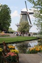 A windmill next to a creek and flowerbeds in the keukenhof gardens in holland
