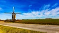 Windmill next to a road and a cultivation field on a wonderful sunny day Royalty Free Stock Photo