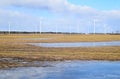 Windmill park in Latvia - view from ploughland with frozen waters.