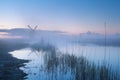 Windmill by river in misty dusk