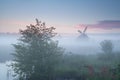 Windmill and river at misty sunrise Royalty Free Stock Photo