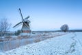 Windmill by river and winter meadow in snow