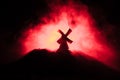 Windmills is silhouette against the night sky. Night decor with old windmill on hill with horror toned foggy background with light Royalty Free Stock Photo