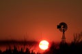 Windmill silhouette at Sunset with a blazing red sky out in the country Royalty Free Stock Photo