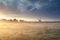 Windmill in summer mist at sunrise