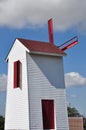 Windmill tower with red sails, shutters and door Royalty Free Stock Photo