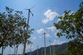 Windmill turbines white steel post technology to generate clean renewable ecological energy with green mountain, blue sky Royalty Free Stock Photo