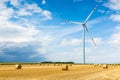Windmill on the wheat field with hay bales Royalty Free Stock Photo