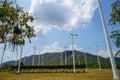 Windmill white post and solar cell panel technology to generate clean renewable energy on grass yard with green mountain, blue sky Royalty Free Stock Photo