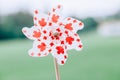 Windmill whizzer with red maple leaves on white background outside outdoors in park. Toy with Canadian flag