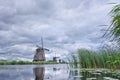 Windmills with dramatic shaped clouds reflected in a canal,