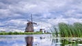Windmills with dramatic shaped clouds reflected in water, Kinderdijk, Netherlands