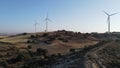 Windmills on a hill surrounded by fields and trees.