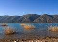 Windmills in the mountains above the lake at sunset in Greece Royalty Free Stock Photo