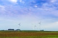 Windmills rotate blades over farmland Royalty Free Stock Photo