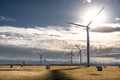 Windmills standing tall overlooking a harvested field with round bales of hay on the Canadian prairies near Pincher Royalty Free Stock Photo