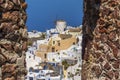 The windmills and white buildings of Oia, Santorini framed by a stone window in Oia castle Royalty Free Stock Photo