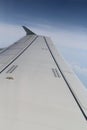 From the window of the aircraft you can see the white wing of the aircraft, sky with blue and white clouds.