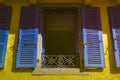 Window with blue and purple shutters against a yellow wall Royalty Free Stock Photo