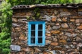 Window with blue rustic wood trim set in the stone wall of an old house Royalty Free Stock Photo