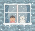 Window on a brick wall on a snowy day. A little boy in the room is surprised, looking at the snow