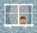 Window on a brick wall on a snowy day. A little boy in the room is surprised, looking at the snow