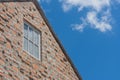 Window on brown brick wall and wooden roof in vintage style with blue sky background. Royalty Free Stock Photo