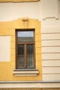 Window with brown frame on light yellow vintage, old building. Architect style classicism concept. Closeup of window in