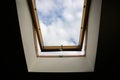 Window in the ceiling. Blue sky with clouds. Attic interior