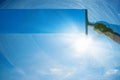 Window cleaner cleaning window with squeegee and wiper on a sunny day with a bright blue sky Royalty Free Stock Photo