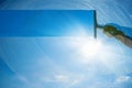 Window cleaner cleaning window with squeegee and wiper on a sunny day with a bright blue sky