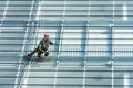 Window cleaner with safety equipment on the shiny glass facade of a skyscraper