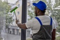 Window cleaner with scraper with sponge for cleaning glass in blue baseball cap Royalty Free Stock Photo