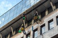 Window cleaners hanging on ropes, cleaning the facade of a building