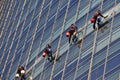 Window cleaning workers hanging outside blue glass office building. Risky job, dangerous work concepts