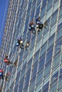 Window cleaning workers hanging outside blue glass office building. Risky job, dangerous work concepts