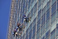 Window cleaning workers hanging outside blue glass office building. Risky job, dangerous work concepts