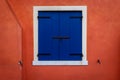 Window with closed blue shutters on an orange wall Royalty Free Stock Photo