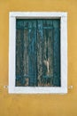 Window with closed old green shutter on yellow wall. Italy, Venice, Burano Royalty Free Stock Photo